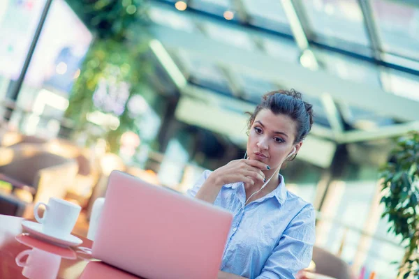 Immagine di donna felice che usa il computer portatile mentre si siede al caffè. Giovane donna seduta in una caffetteria e che lavora su un computer portatile . — Foto Stock