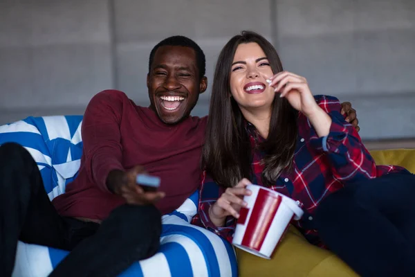 Portrét mladého páru sedícího na pohovce a pozoruje film s výrazem na tvářích — Stock fotografie