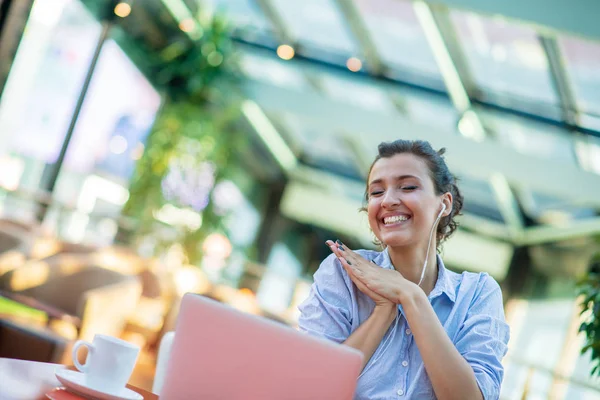 Зображення щасливої жінки, яка використовує ноутбук, сидячи в кафе. Молода жінка сидить у кав'ярні і працює на ноутбуці . — стокове фото