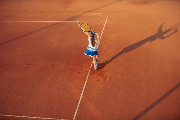 Жінка грає в теніс на глиняному дворі, зі спортивним вбранням і здоровим способом життя — стокове фото