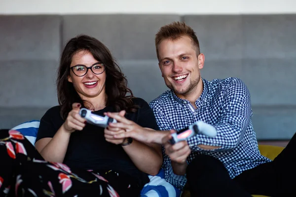 Joven pareja sonriente jugando videojuegos en casa . — Foto de Stock