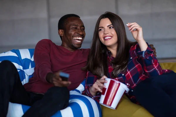 Retrato de una joven pareja sentada en un sofá viendo una película con expresión en sus rostros — Foto de Stock