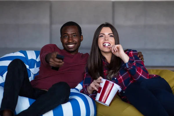 Retrato de una joven pareja sentada en un sofá viendo una película con expresión en sus rostros — Foto de Stock