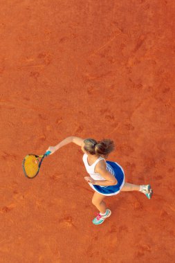 Maç sırasında sahada bir kadın tenisçi havadan çekilmiş. Tenis oynayan genç bir kadın. Yüksek açı görünümü.
