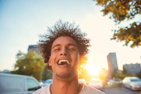 스마트 폰을 사용하여 행복 미소 도시 힙스터 젊은 남자. 렌즈 플레어와 일몰에 모바일 스마트 폰을 들고 아프리카 계 미국인 십대 — 스톡 사진