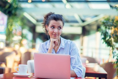 Kafede otururken dizüstü bilgisayar kullanan mutlu kadın görüntüsü. Bir kafede oturan ve dizüstü bilgisayar üzerinde çalışan genç kadın.
