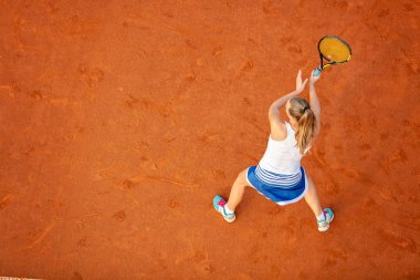 Maç sırasında sahada bir kadın tenisçi havadan çekilmiş. Tenis oynayan genç bir kadın. Yüksek açı görünümü.
