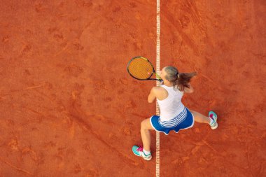Maç sırasında sahada bir kadın tenisçi havadan çekilmiş. Tenis oynayan genç bir kadın. Yüksek açı görünümü.