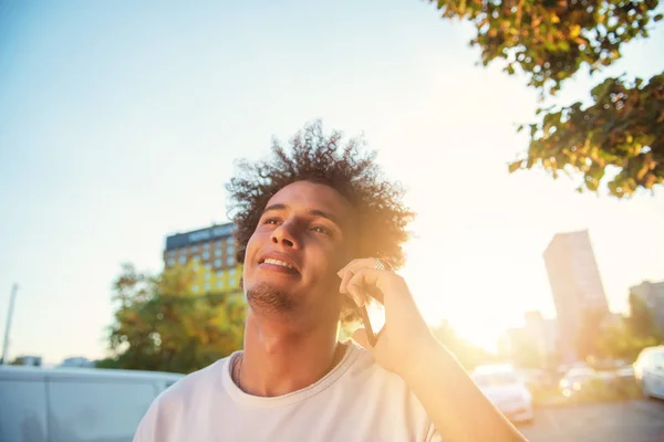 스마트 폰을 사용하여 행복 미소 도시 힙스터 젊은 남자. 렌즈 플레어와 일몰에 모바일 스마트 폰을 들고 아프리카 계 미국인 십대 — 스톡 사진