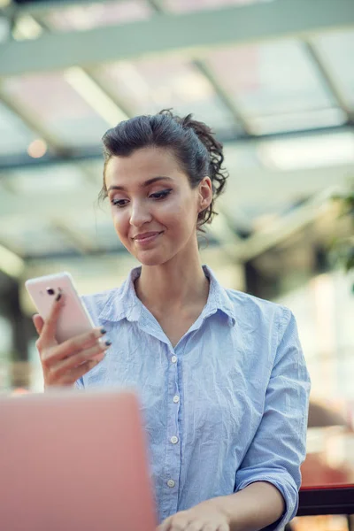 Porträt eines verspielten jungen Mädchens, das ein Selfie mit dem Handy macht, während es mit dem Laptop in einem Café im Freien sitzt — Stockfoto