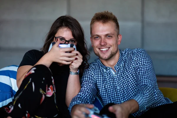 Νεαρό χαμογελαστό ζευγάρι που παίζει βιντεοπαιχνίδια στο σπίτι. — Φωτογραφία Αρχείου