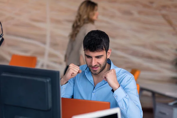 Oldalnézetből. Fiatal szakállas üzletember kék inget visel, ül az asztalnál, és használ laptop. Szabadúszóként ellenőrzése e-mail. — Stock Fotó