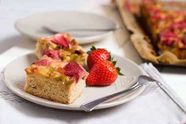 Çilek ve ravent pasta tatlı çatal ile ve tüm pasta parça arka planda devam eder.