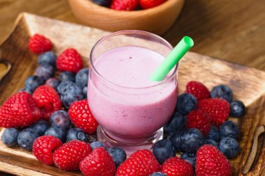 Milk shake orman meyve (ahududu, çilek ve yaban mersini) cam cup bardağı taşıran damla ile birlikte içmek için hazırlanan