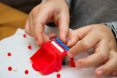 Küçük çocuğun elleri küçük nesneleri (ince motor işleme pratik renkli mermerler ile oynamak)