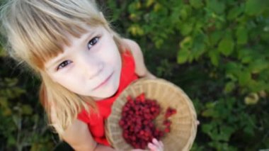 Kız bahçede olgun kırmızı, sulu ahududu yiyor.