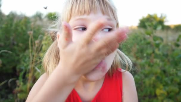 Mädchen isst reife rote saftige Himbeere im Garten — Stockvideo