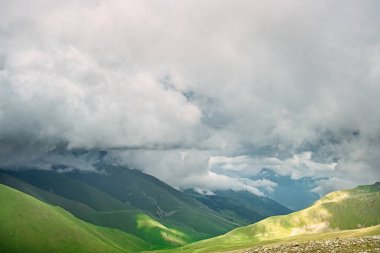 dağ Vadisi ve dağ zirveleri düşük yoğun bulutlar manzara resimde arka tarafından kapalı yamaçlarında kar kalıntıları ile