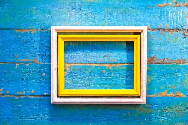 yellow frame inside a white frame for photos and images with a blank space inside on a blue textured wooden wall