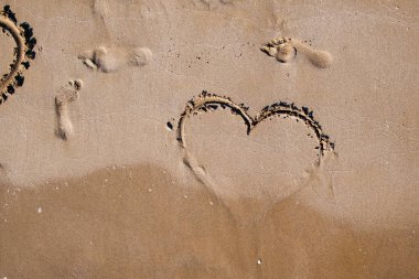 aşk kalp arması deniz kum üzerinde insan ayak izleri yanında sıcak yaz gününde boyalı