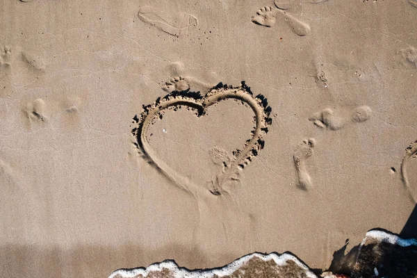 aşk kalp arması deniz kum üzerinde insan ayak izleri yanında sıcak yaz gününde boyalı