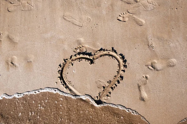 aşk kalp arması deniz kum üzerinde insan ayak izleri yanında sıcak yaz gününde boyalı