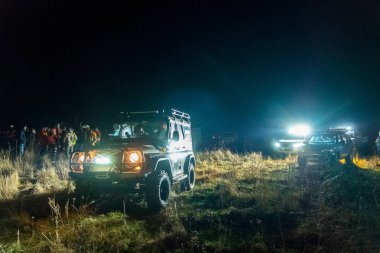 Işıklar açık parlak ışıklar arka plan ve insanların kalabalıklar karanlık bir gece başında ile Off-Road spor araba duruyor