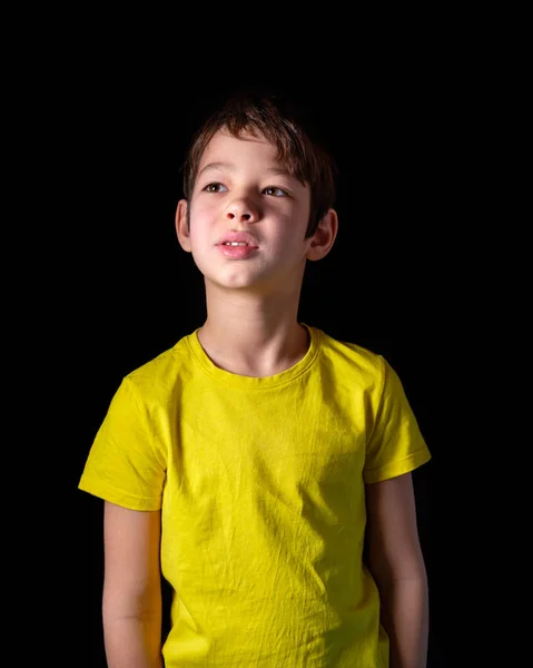 boy in yellow tank top pensive face, dreaming on black background