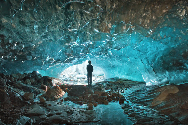 silhouette of a man in a glacier cave of blue ice Dombay Karachay-Cherkessia Russia