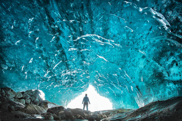 silhouette of a man in a glacier cave of blue ice Dombay Karachay-Cherkessia Russia