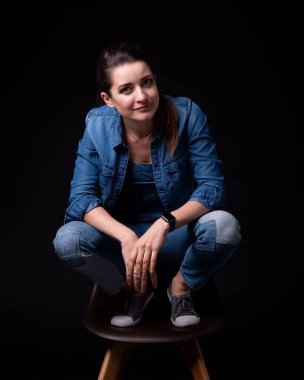 sandalye üzerinde mavi kot ceket ve pantolon standları bacak kadar esmer kız siyah arka plan üzerine yakın