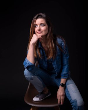 sandalye üzerinde mavi kot ceket ve pantolon standları bacak kadar esmer kız siyah arka plan üzerine yakın