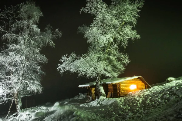 Dřevěná Bouda Jasným Světlem Okně Vedle Vysoký Strom Pokryté Sněhem — Stock fotografie