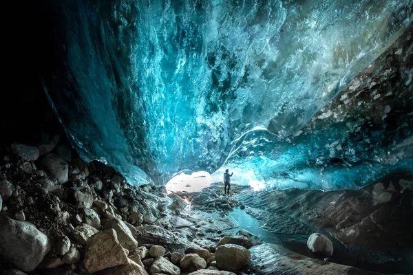 an ice cave in a mountain glacier, a column of the purest ice hangs above the stones of the Alibek cave, Dombay glacier, Russia