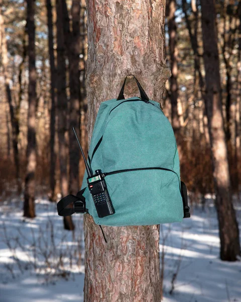 light city backpack with a walkie-talkie hanging on a tree trunk in the forest