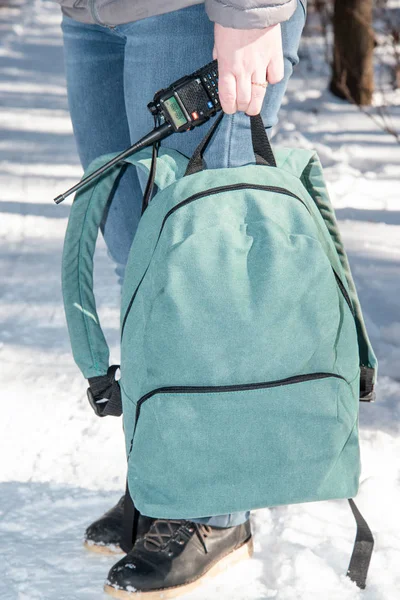 girl with a city backpack and a walkie-talkie standing in the woods in winter