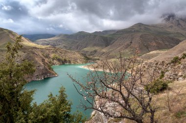 Bulutlarda dağ zirveleri ile geçitte dağ gölü. Rusya Kabardey-Balkarya Cumhuriyeti'nde Bylym Gölü