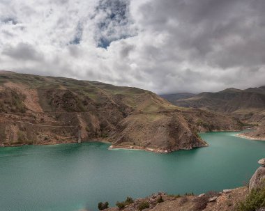 Bulutlarda dağ zirveleri ile geçitte dağ gölü. Rusya Kabardey-Balkarya Cumhuriyeti'nde Bylym Gölü