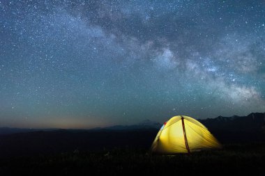 Samanyolu ile gece gökyüzüne karşı sarı renk turist çadırı
