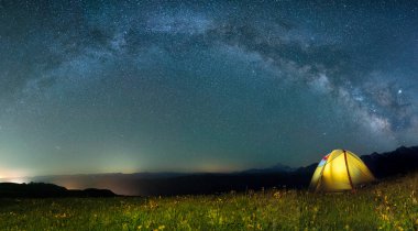 Samanyolu ile gece gökyüzüne karşı sarı renk turist çadırı