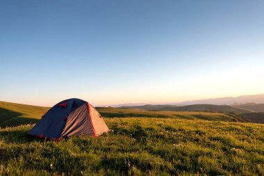 turist çadırı dağların bir arka plan üzerinde sabah yeşil çim üzerinde duruyor