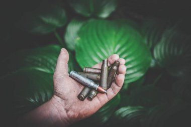 yeşil yaprakları bir arka plan karşı kirli çocukların elinde boş atış mühimmat ve tüm mühimmat