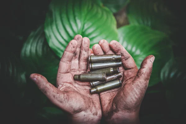 空射弹药和整个弹药在肮脏的儿童手中的绿叶背景 — 图库照片