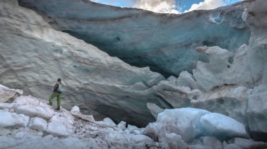 Buz duvarının yakınındaki bir dağ buzulunda insan, Dombay 'daki sonsuz buz Alibek buzulu.