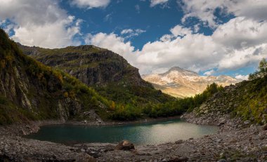 Dağlar ve sonbahar ormanlarıyla çevrili yeşil bir göl. Dombay 'daki Turye Gölü.