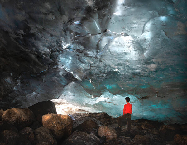 Man, teenager stands in the ice cave Alibek glacier in Dombay