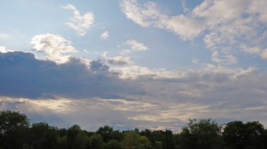 Yaz manzarası. Yeşil çimenler ve ağaçlar bulutlarla mavi gökyüzüne karşı. Doğa.