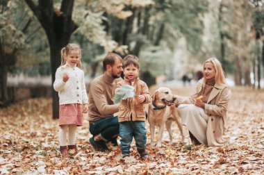 Sonbahar parkında mutlu bir beyaz aile, Anne baba oğul ve köpek Labrador, sonbahar sezonu