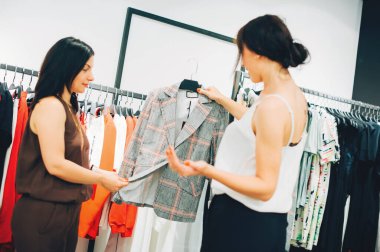 Tarz sahibi olmanı istiyorum! Moda mağazasında çalışırken müşterisine kıyafet seçmeye çalışan güzel bir genç kadın. Moda tasarımcısı mağazada yeni koleksiyon ve eğilimleri gösterir