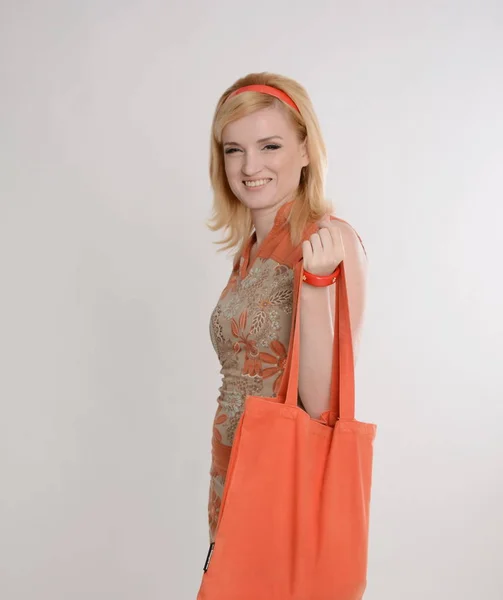 Beautiful girl posing, orange canvas bag in hands. — Stock Photo, Image